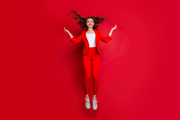 Full size photo of charming lady with bright lips stick jumping holding hands isolated red background - Foto, afbeelding