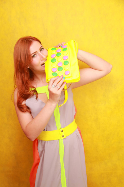 pretty redheaded girl in bright summer dress with yellow bright leather bag - Foto, afbeelding