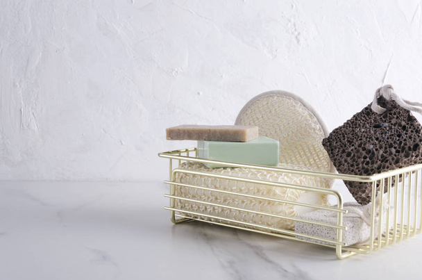 Metal basket for bath accessories.Natural organic soap, sponges, pumice on the white table.Empty space for text - Фото, зображення