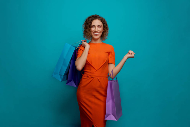 Front view of happy woman keeping colorful paper bags - Valokuva, kuva