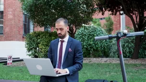 junger Mann im Businessanzug arbeitet am Laptop aus dem Büro heraus - Filmmaterial, Video