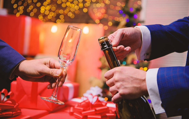 Drink champagne or sparkling wine. Celebrate new year with champagne. Last minute before new year. New year countdown. Hands opening champagne bottle and hold glass christmas decorations background - 写真・画像
