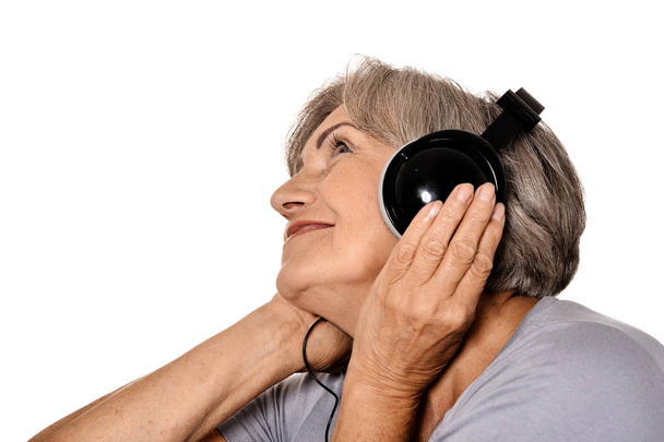 senior woman listen a music in headphones isolated on white background - Fotografie, Obrázek