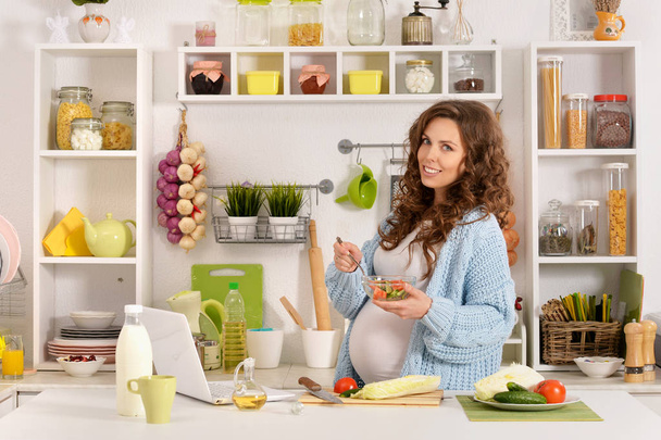 Young pregnant woman having breakfast at kitchen - Fotó, kép
