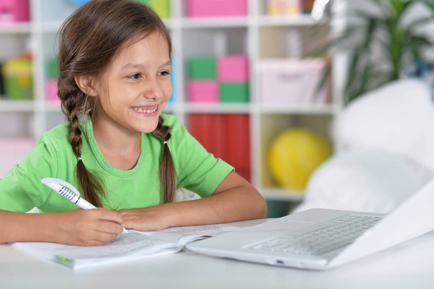 Portrait of concentrated little girl with laptop studying  - Foto, imagen