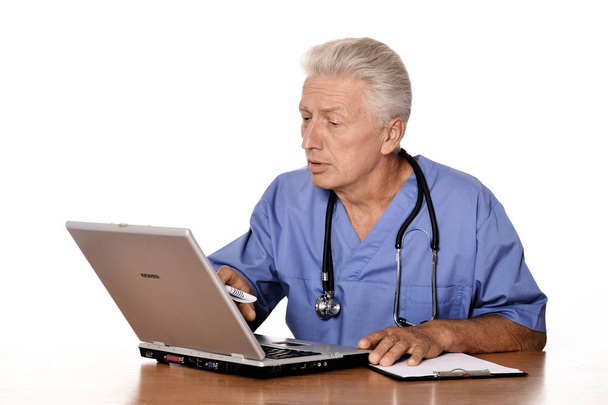 Elderly doctor with a laptop on white background - Foto, imagen