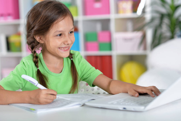 Portrait of concentrated little girl with laptop studying  - Photo, image