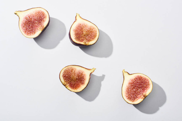 top view of ripe cut delicious figs on white background - Foto, afbeelding