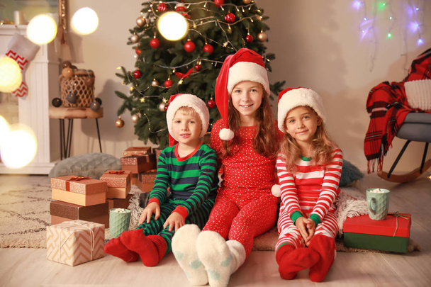 Petits enfants mignons dans les chapeaux du Père Noël la veille de Noël à la maison
 - Photo, image