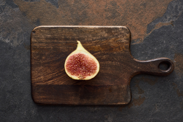 top view of ripe cut delicious fig on wooden cutting board on stone background - Photo, Image