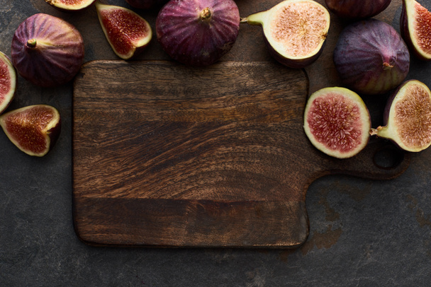 top view of ripe whole and cut delicious figs near cutting board on stone background - Photo, image