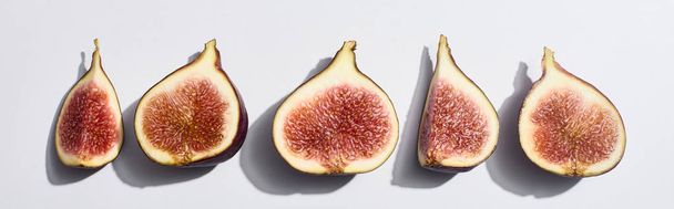 panoramic shot of ripe cut delicious figs in row on white background - Photo, Image