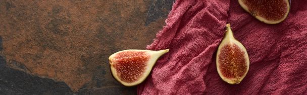 panoramic shot of cut delicious figs on rustic red cloth on stone background - Photo, image