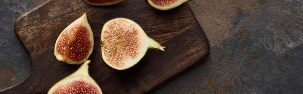 top view of cut fresh delicious figs on cutting board on stone background, panoramic shot - Foto, Imagem