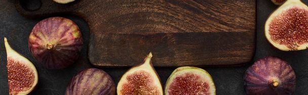 panoramic shot of ripe figs around wooden cutting board on stone background - Foto, Imagem