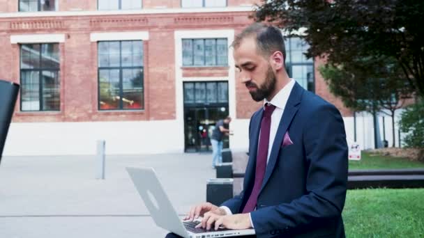 Joven hombre de negocios que trabaja en el portátil en un distrito de negocios, cerca de cámara lenta
 - Metraje, vídeo
