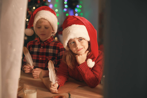 Lindos niños pequeños escribiendo carta a Santa Claus en la víspera de Navidad en casa. Vista a través de ventana
 - Foto, Imagen