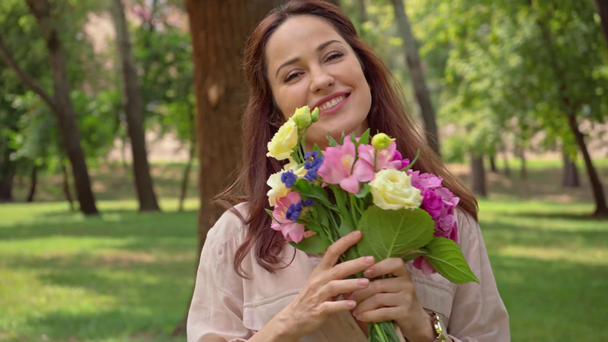 happy woman with flowers in park - Materiał filmowy, wideo