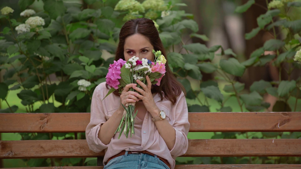 álmodozó nő csokor ül a padon a parkban - Felvétel, videó