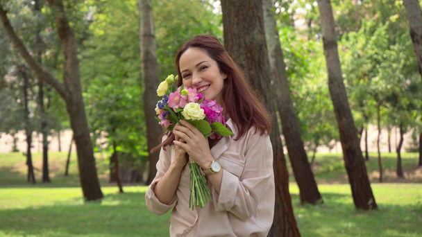 parkta çiçeklerle yürüyen mutlu kadın - Video, Çekim