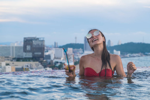 красива дівчина в сонцезахисні окуляри з коктейлем в басейні з панорамним видом на місто Паттайя. Літній відпочинок відпустку - Фото, зображення