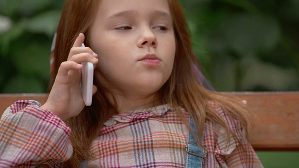 emocjonalne dziecko rozmawia na smartfonie w parku - Materiał filmowy, wideo
