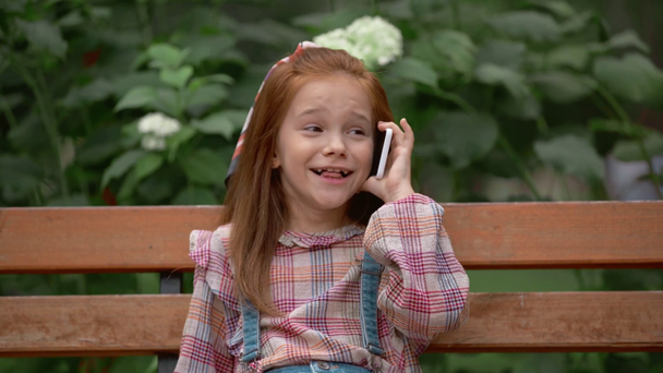 szczęśliwy adorable dziecko rozmawia na smartfonie w parku - Materiał filmowy, wideo