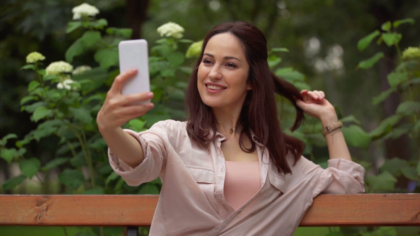 Ευτυχισμένη γυναίκα λήψη selfie στο πάρκο - Πλάνα, βίντεο