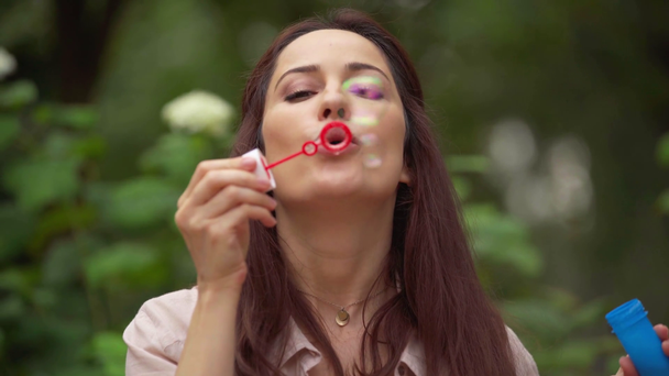 happy woman blowing soap bubbles in park - Footage, Video
