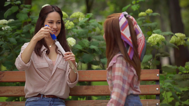 happy mother and daughter blowing soap bubbles in park - Video, Çekim