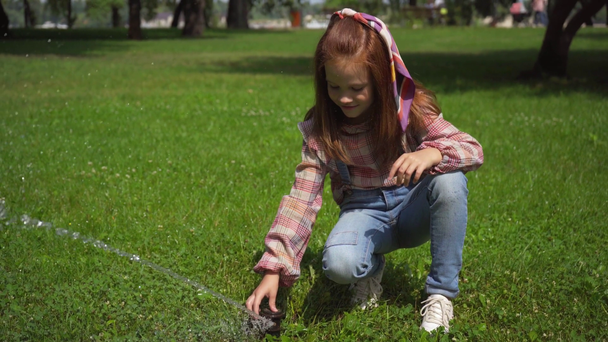 leuke Kid spelen met water stream op groen gras - Video