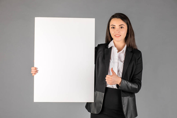 Молода усміхнена жінка вказує на порожній білий лист для реклами
 - Фото, зображення