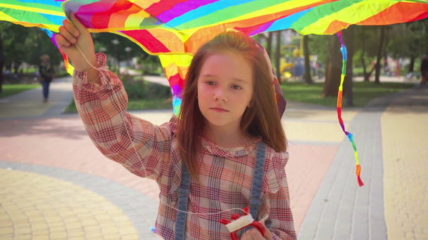 niño sonriente caminando con cometa arco iris en el parque
 - Metraje, vídeo