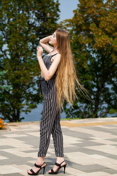 Young beautiful woman in striped trousers walking on the street, - Foto, imagen