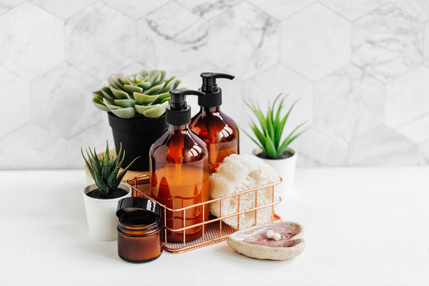 Bathroom accessories, natural cosmetics products and tools with green plant on white table inside a bathroom background. - Photo, Image