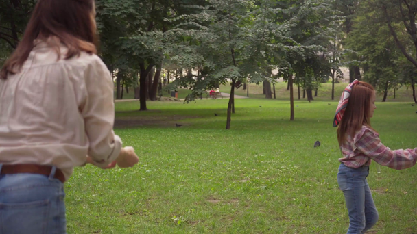 Mutter und Tochter blasen gemeinsam Seifenblasen im grünen Park - Filmmaterial, Video