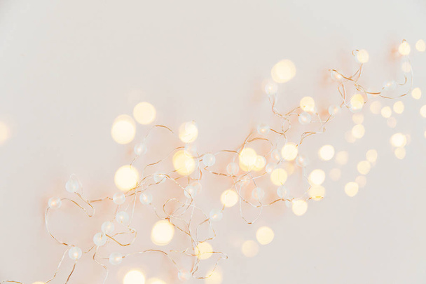 Warm light garlands on pink background, festive decorations. Flat lay, top view - 写真・画像