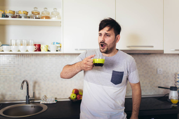 Handsome man on kitchen drinking coffee in the morning. - Фото, зображення