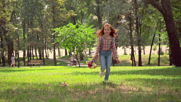 niña pelirroja corriendo con flores en verde parque soleado
 - Imágenes, Vídeo