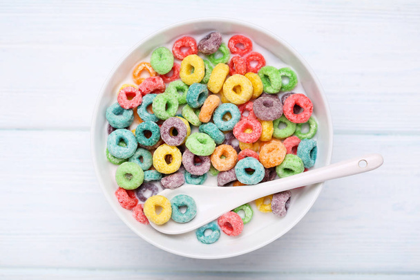 Colorful corn rings in bowl with milk and spoon on white wooden  - Foto, Bild