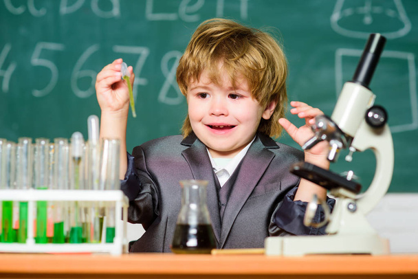 Explore biological molecules. Toddler genius baby. Boy near microscope and test tubes in school classroom. Science concept. Gifted child and wunderkind. Kid study chemistry school. School education - 写真・画像
