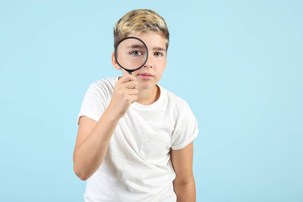 Young boy with magnifying glass on blue background - Photo, image
