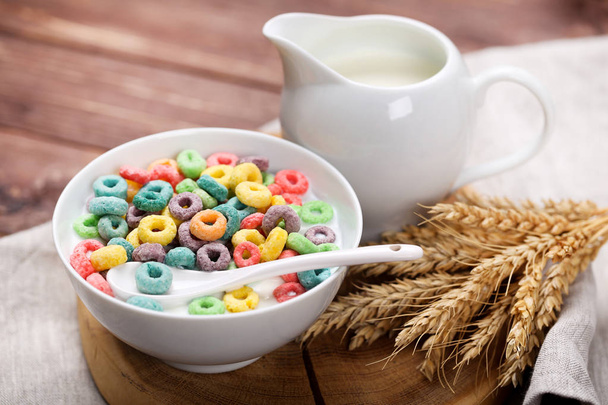 Colorful corn rings in bowl with milk and wheat ears on wooden t - Фото, зображення