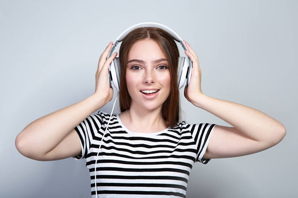 Young beautiful woman with headphones on grey background - Fotografie, Obrázek