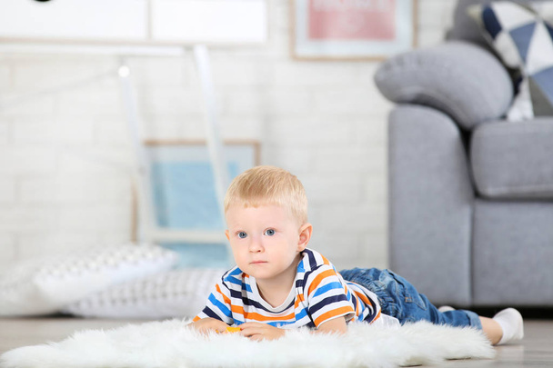 Little boy lying on white carpet at home - Foto, Imagen