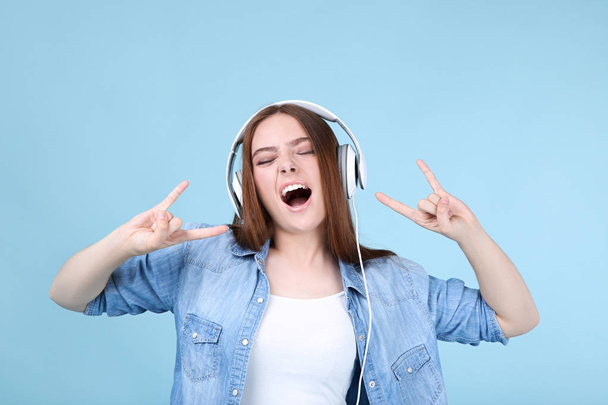 Young beautiful woman with headphones on blue background - Фото, изображение
