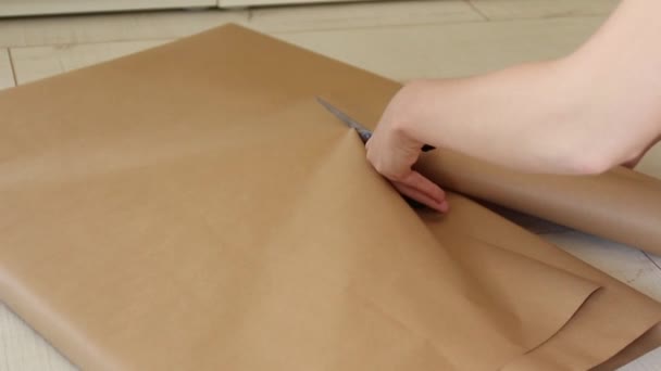 Τα γυναικεία χέρια έκοψαν το χαρτί δώρου της χειροτεχνίας. Προετοιμασία για ένα νέο έτος, γενέθλια ή Χριστούγεννα - Πλάνα, βίντεο