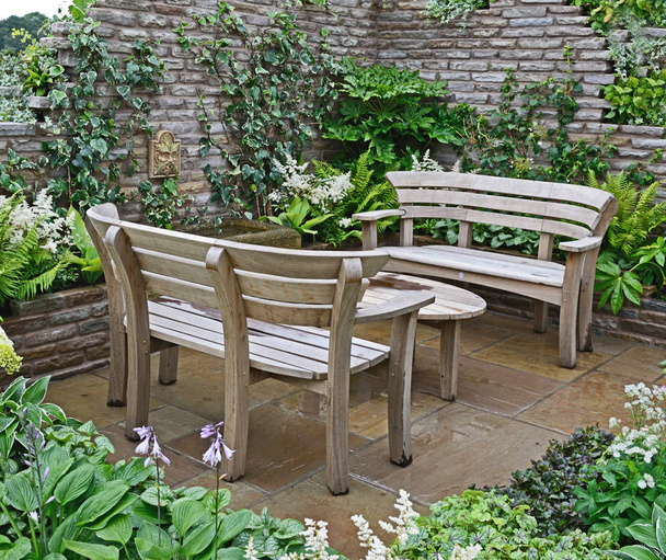 Primer plano de asientos de jardín de madera en una terraza de jardín amurallada seculada
 - Foto, imagen