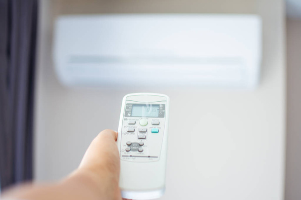 menschlicher Handdruck auf Fernbedienung der Klimaanlage mit heißem Wasser - Foto, Bild