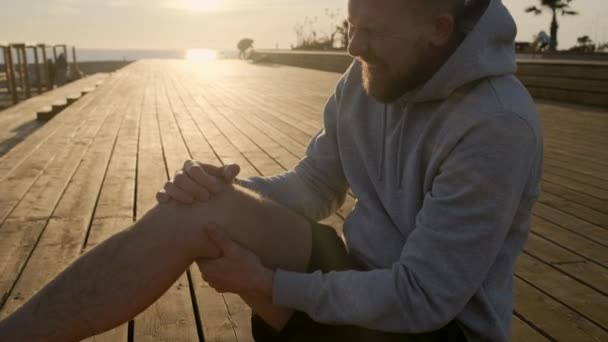 Mies tuntee kipua vedetty jalka harjoittelun jälkeen, istuu maassa, ulkona
 - Materiaali, video